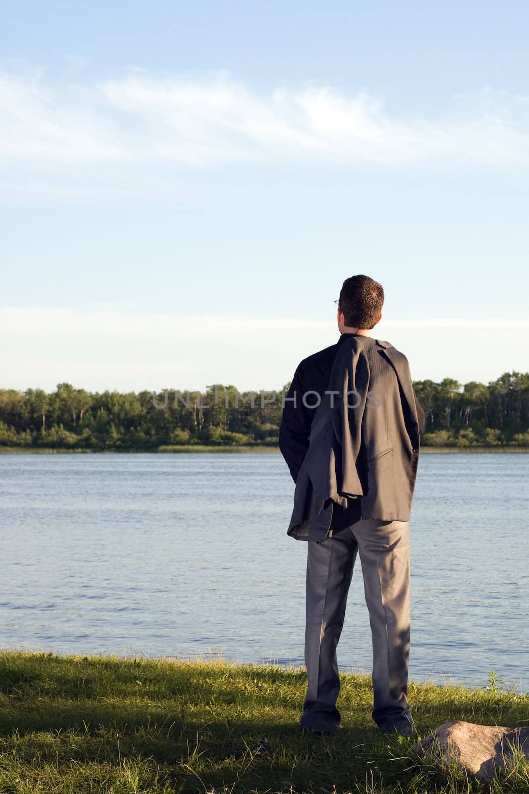 A businessman relaxing by a small lake after work