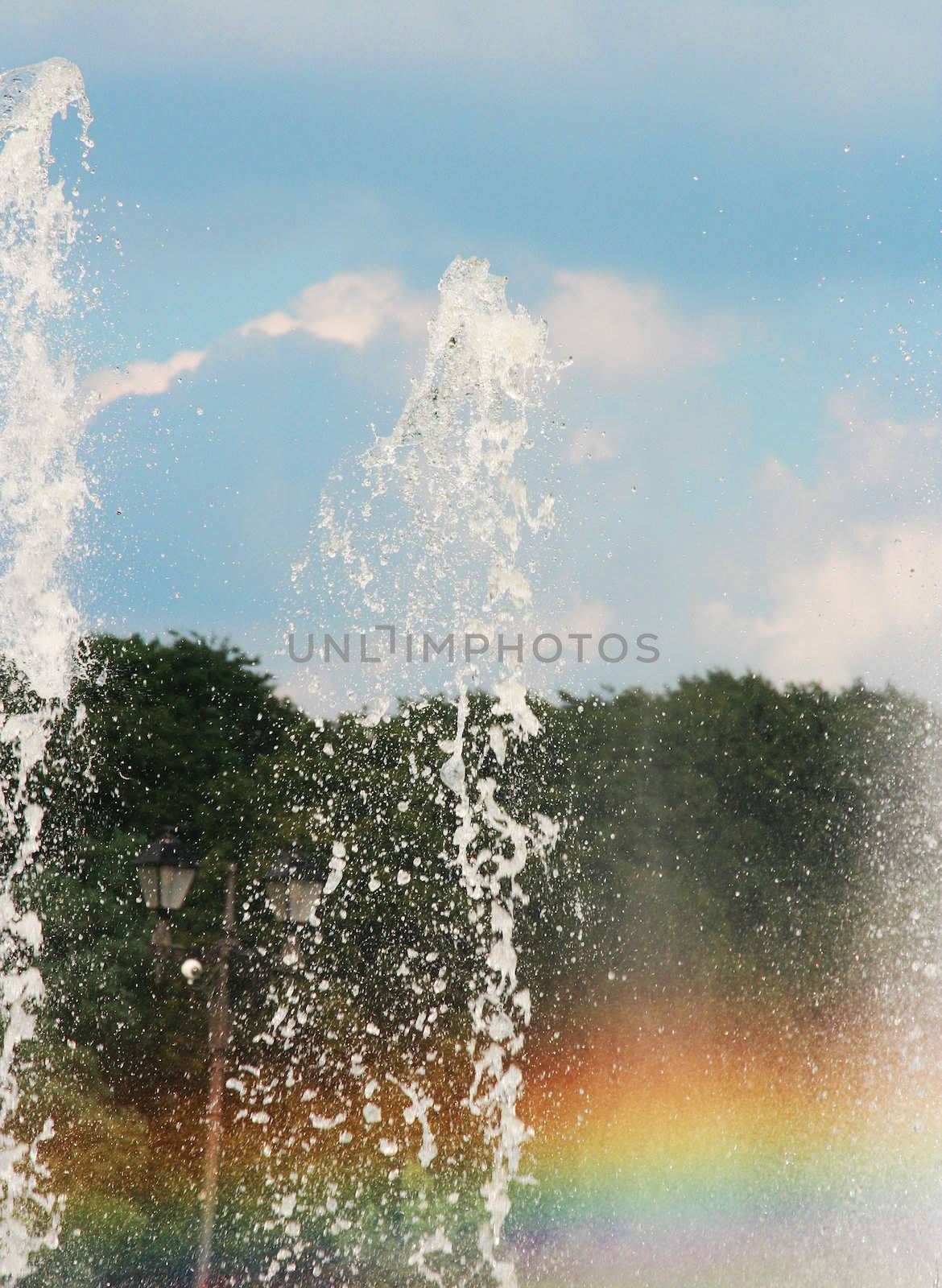 Beautiful rainbow above sparks of a fountain and the sky