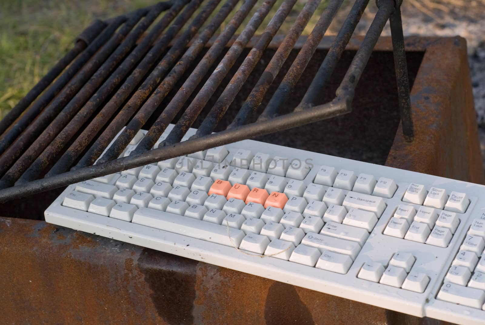 A computer keyboard in a fire pit with the word burn on it