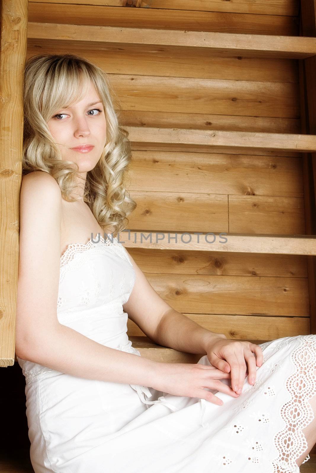 The blond girl in a white dress near a wooden ladder