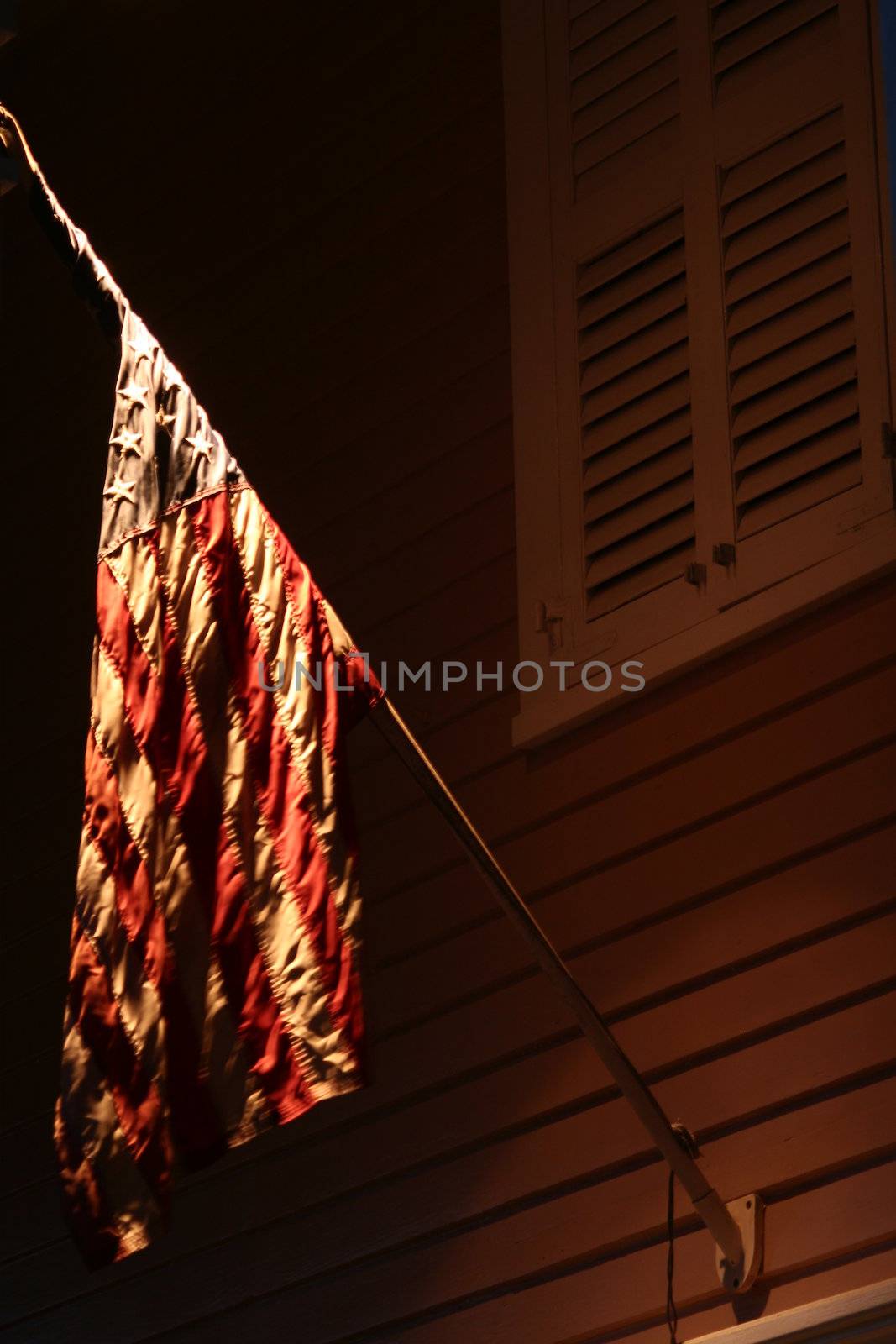 An American flag hangs at night under a light.