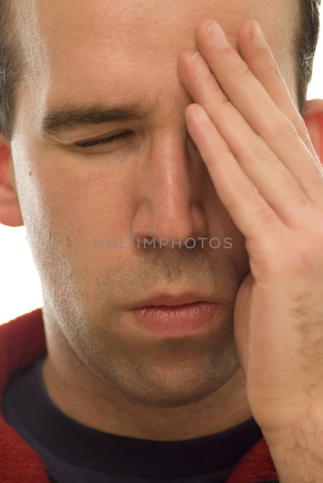 Close-up view of a man's face with his hand on his forehead indicating he has a headache