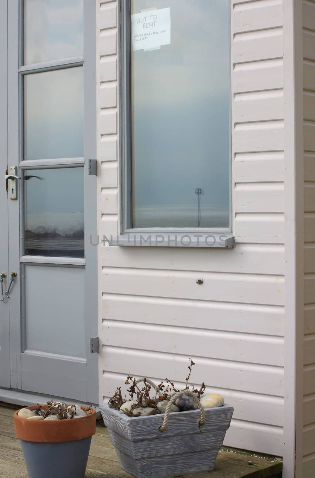 A wooden beach hut with a sign in the window advertising its availablity to be rented. Located in Christchurch, Dorset Hampshire UK.