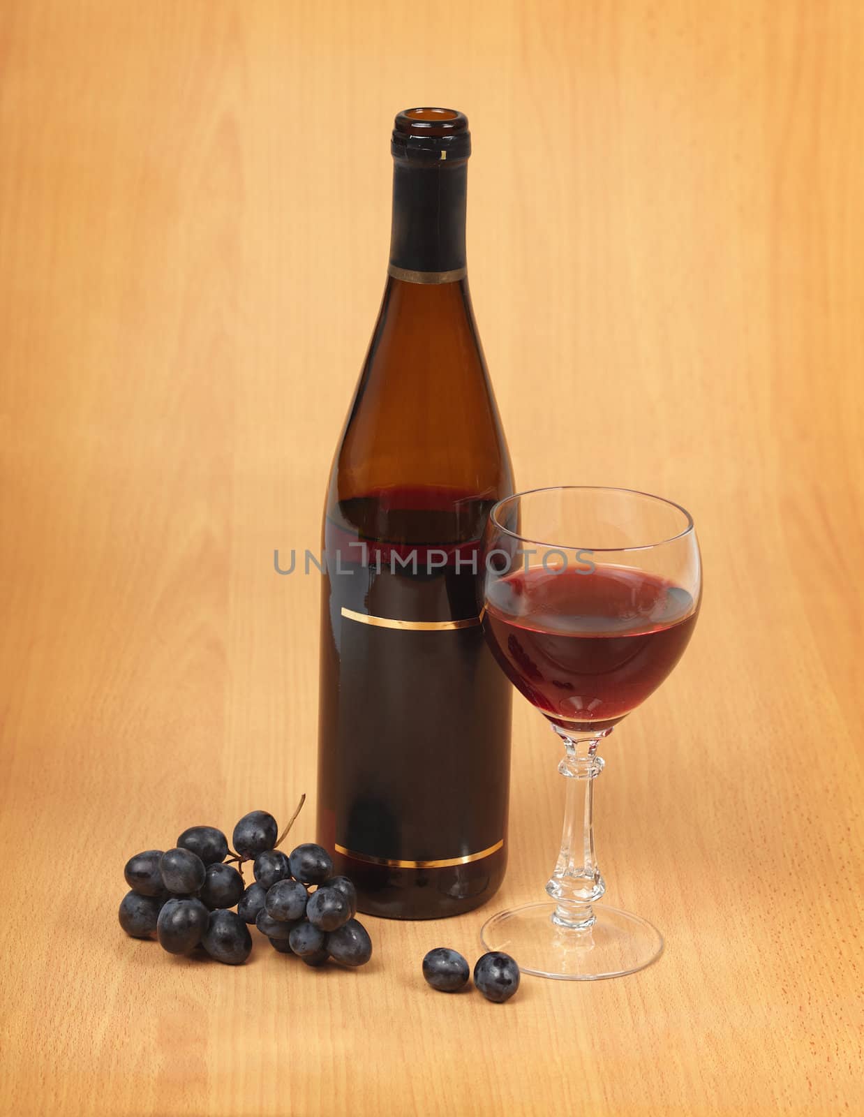 Bottle, wine glass and grapes on wood background
