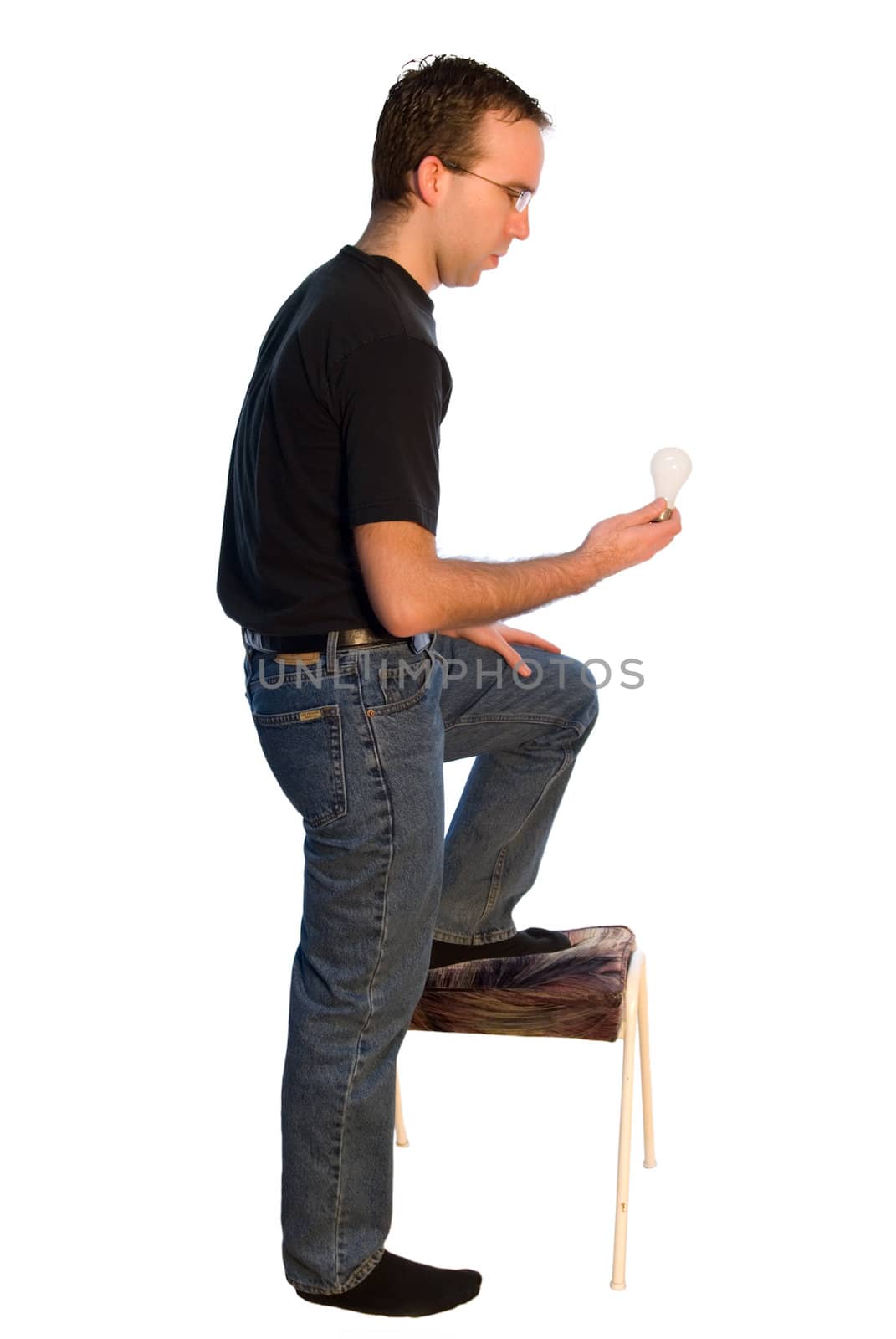 Young man standing on a stool to change a lightbulb