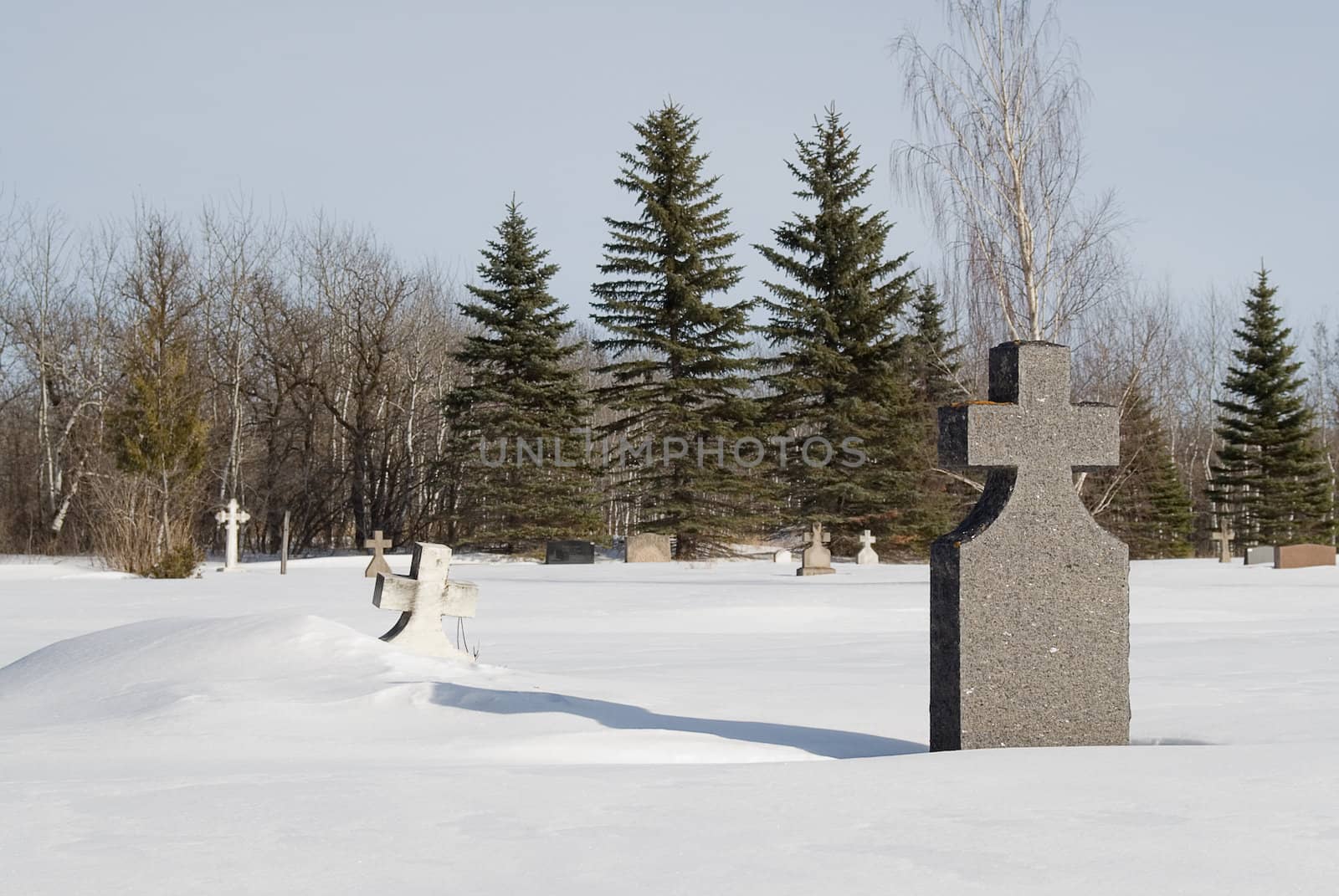 A grave with a tombstone in the middle of winter with snow on the ground