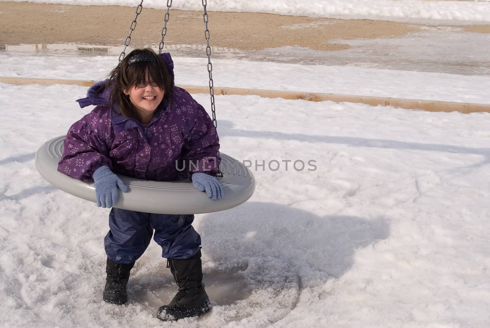 A young girl on a plastic tire swing in a school playground