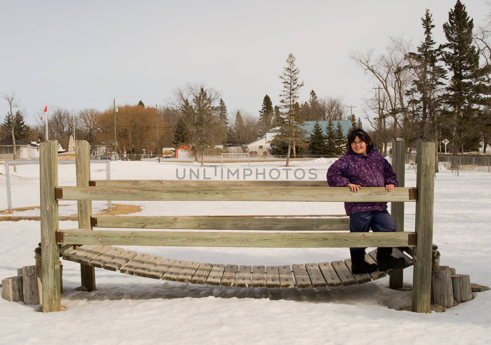 A girl standing on a bouncing wooden bridge, in the middle of winter