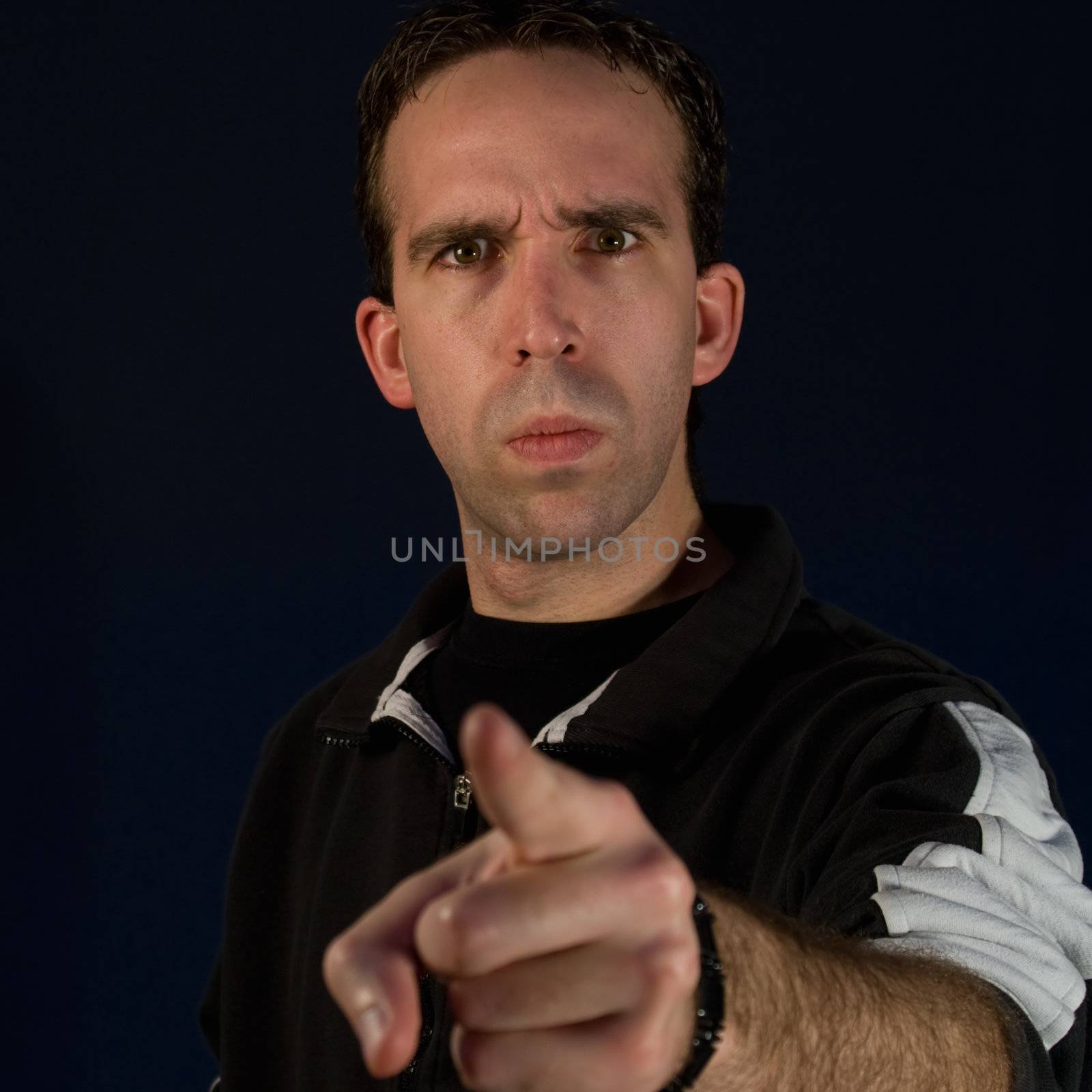 An angry man with a mad expression on his face, pointing his finger at the camera