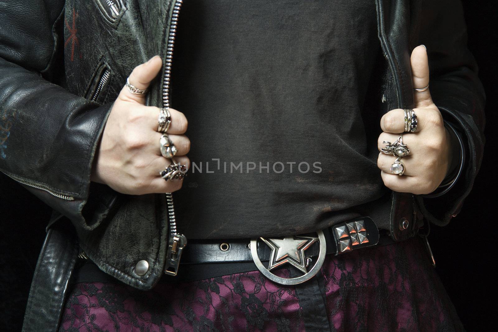 Caucasian woman's hands with silver rings holding onto black leather jacket.