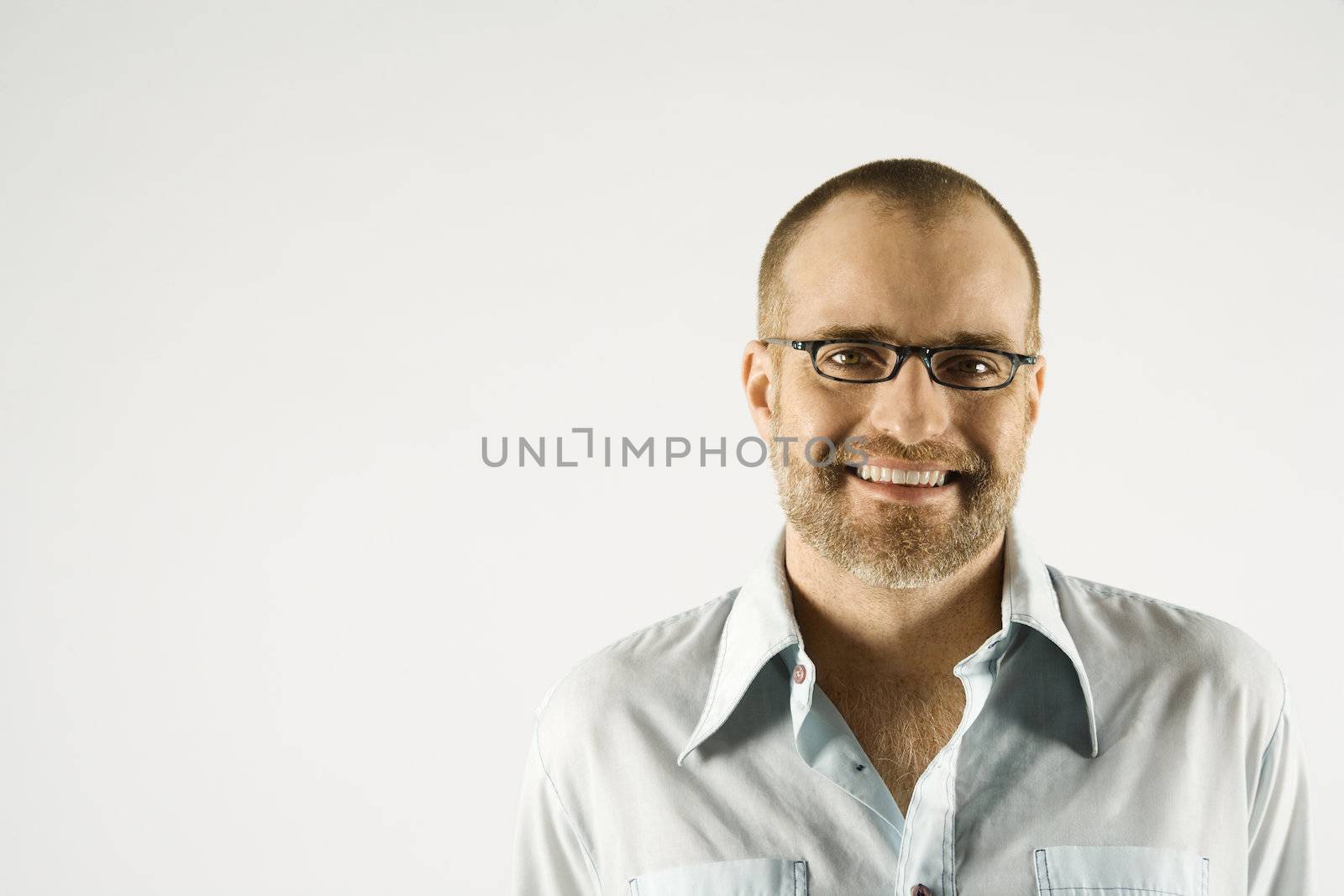 Head and shoulder portrait of Caucasian man smiling against white background.