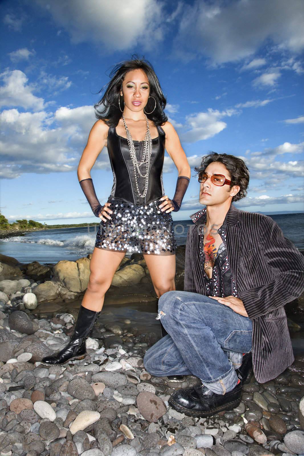 Caucasian young male adult and African American female on rocky beach.