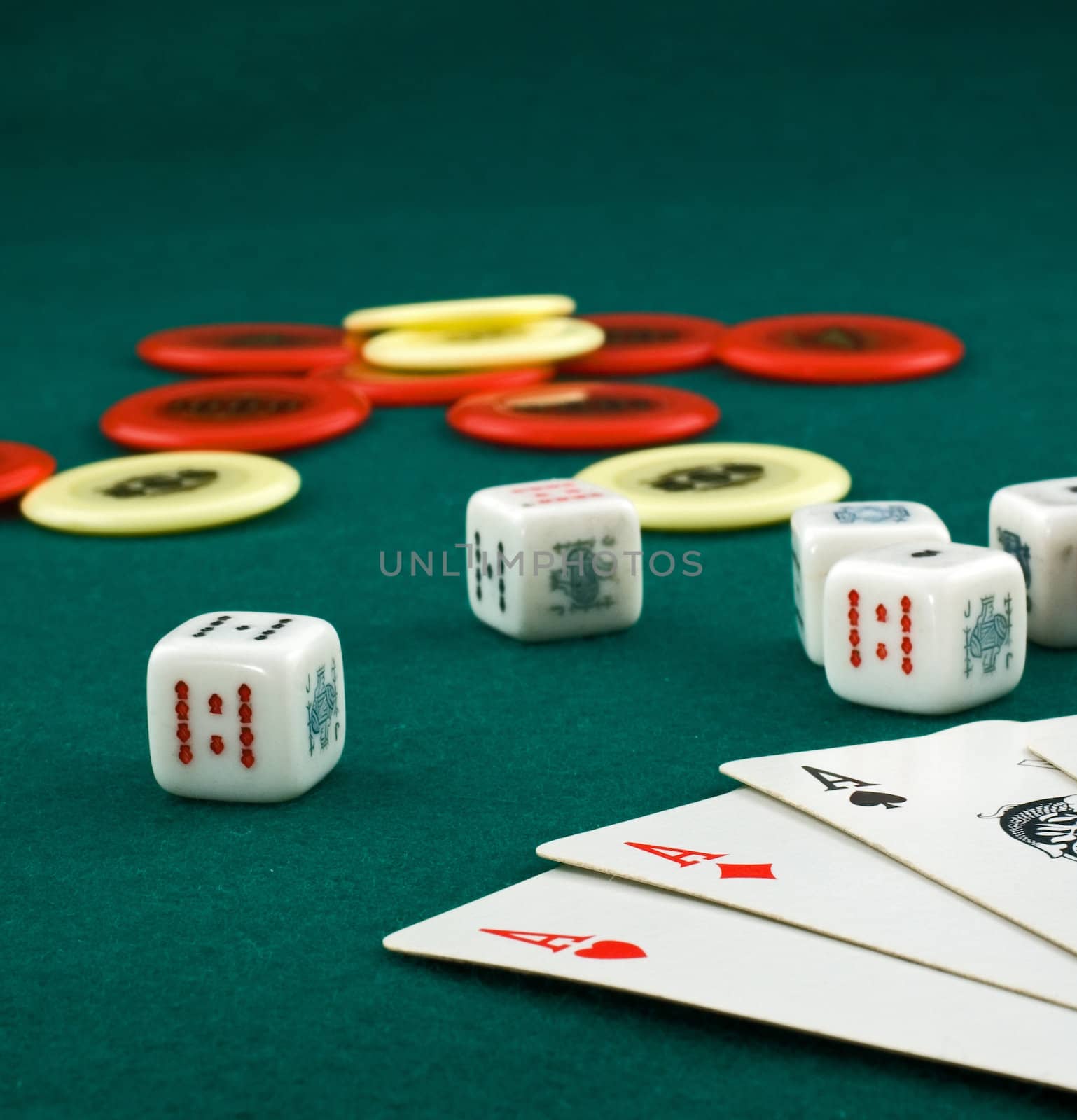 Aces, dice and chips on green carpet with shallow depth of field