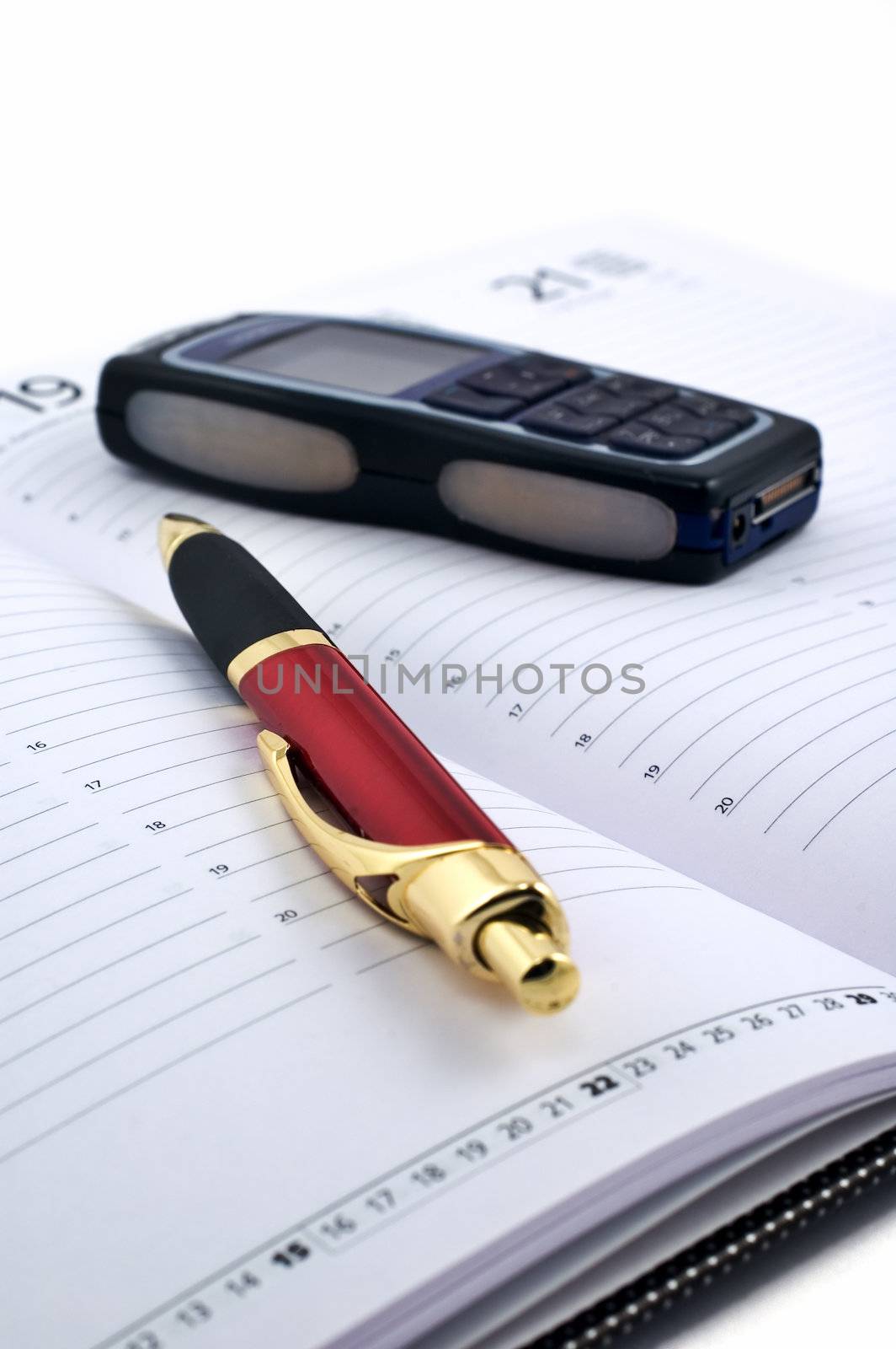 Pen and cell phone on open agenda with shallow depth of field