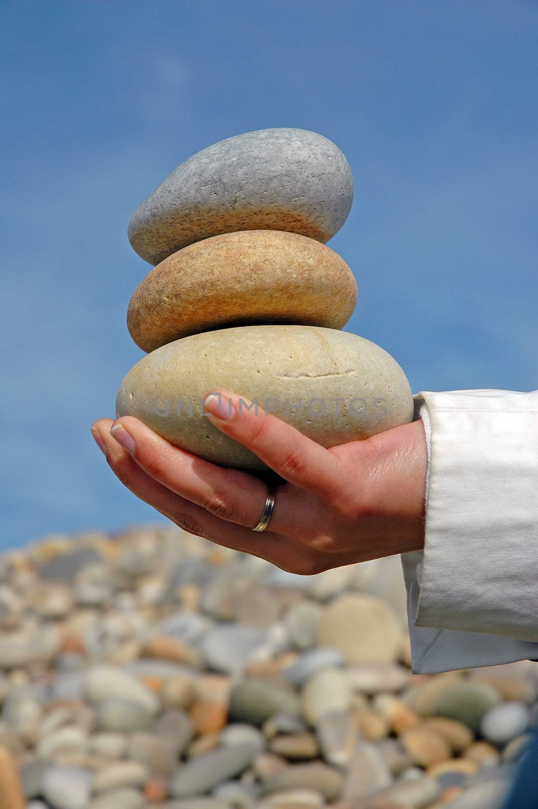 woman hand with pebble stack over beach by raalves