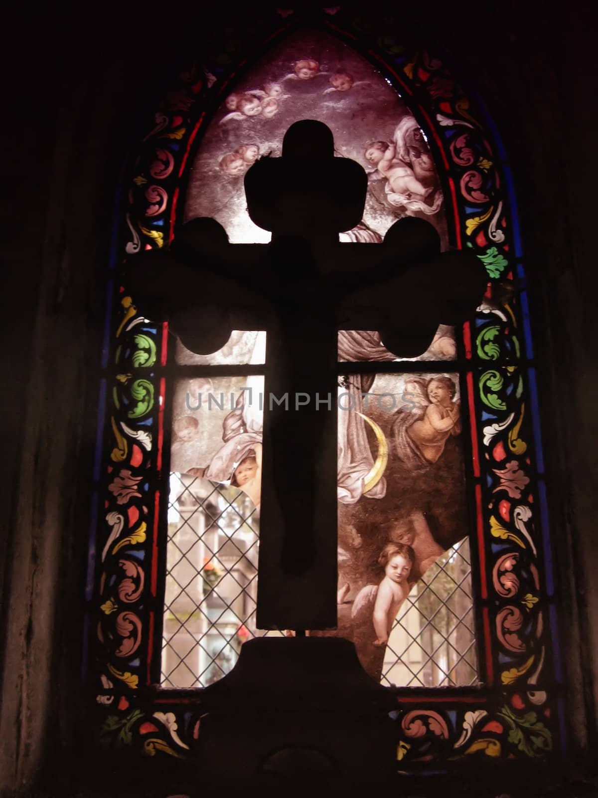a Cross in front of a stained glass in a funeral chapel