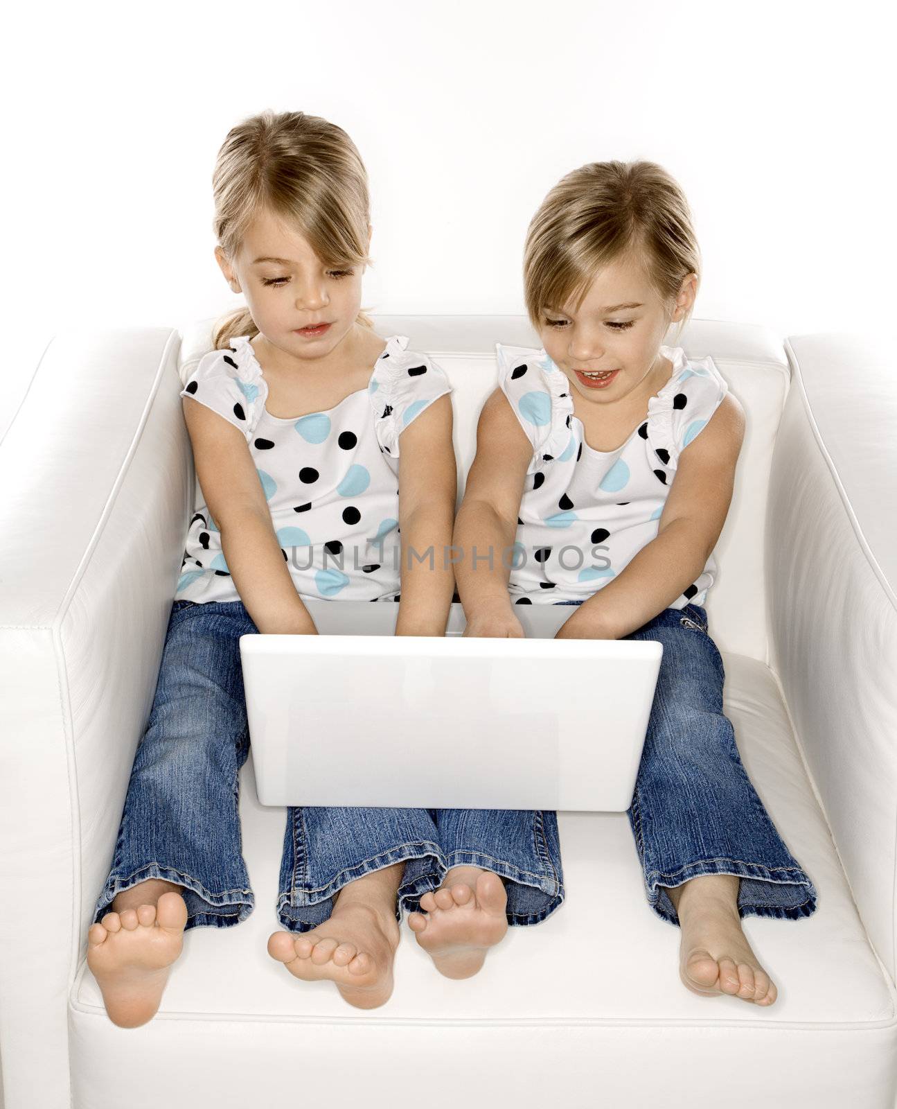 Girl twins with laptop computer. by iofoto