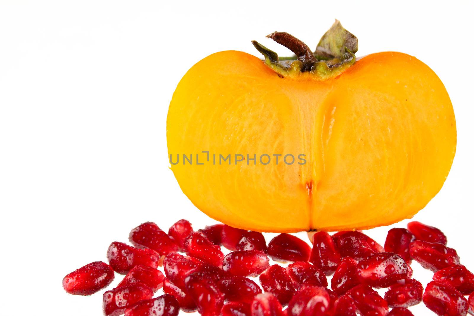 Grains pomegranate and a persimmon removed close up on a white background without isolation