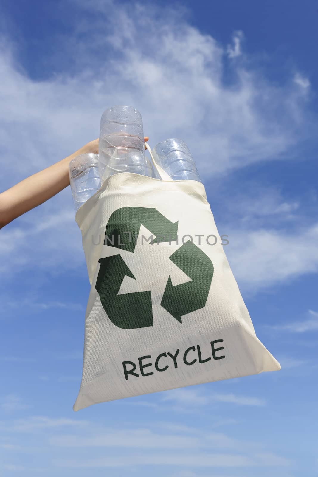 recycling: hand holding bag with plastic bottles against blue sky