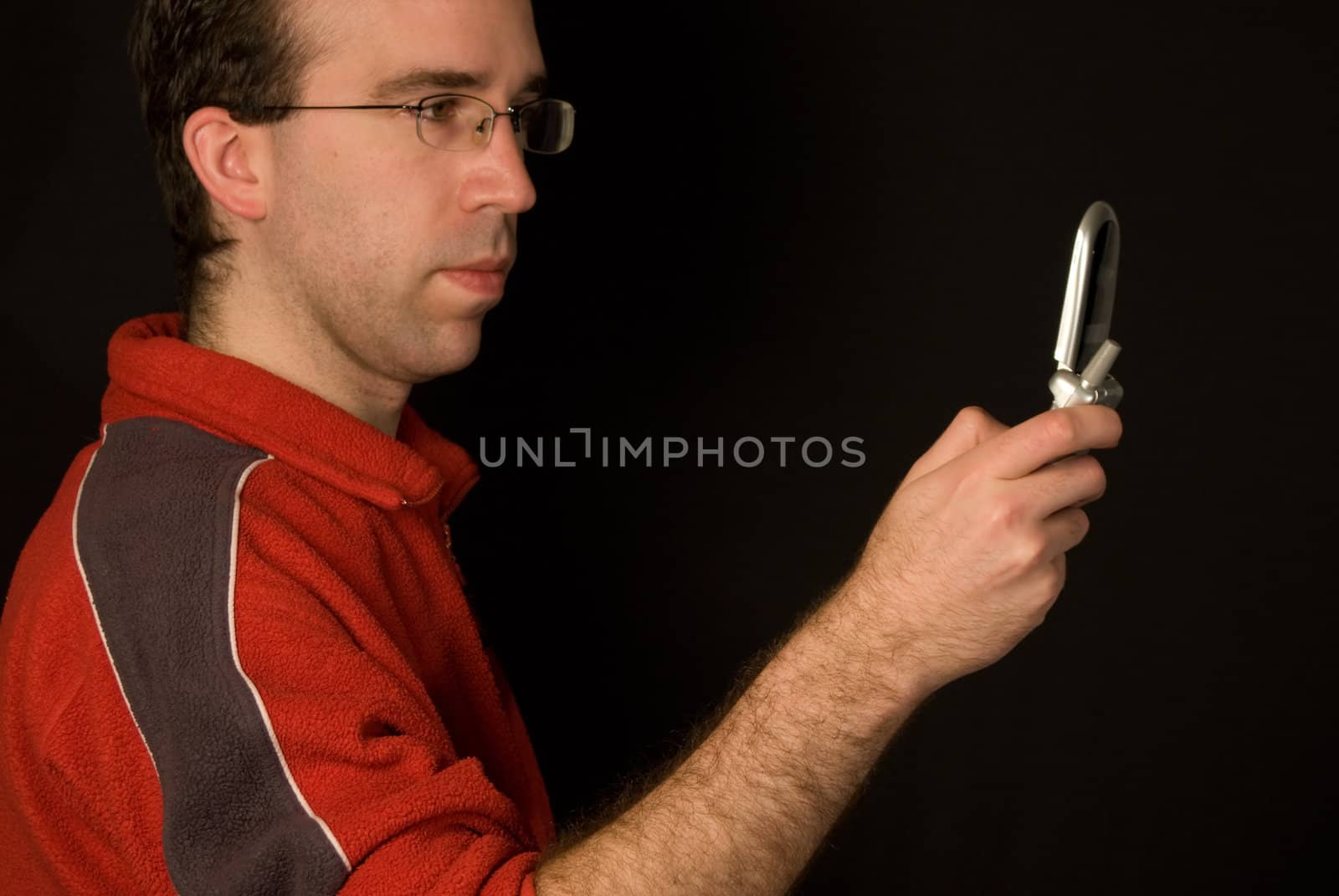 Man writing a text message on his cellphone, isolated against a dark background