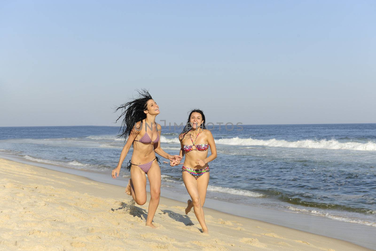 holiday fun: two girls having a racing duel on the beach