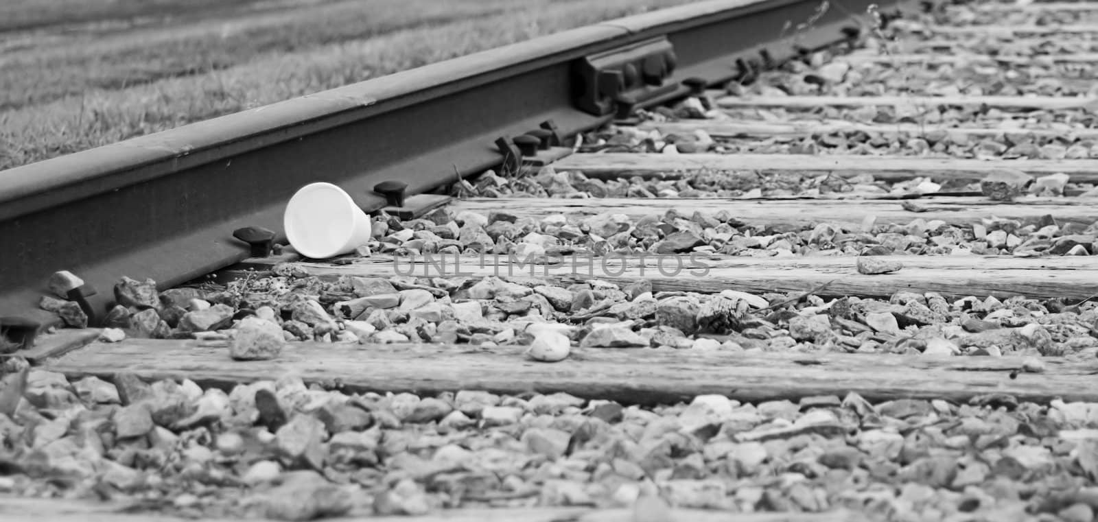 A styrofoam cup laying on some railroad tracks