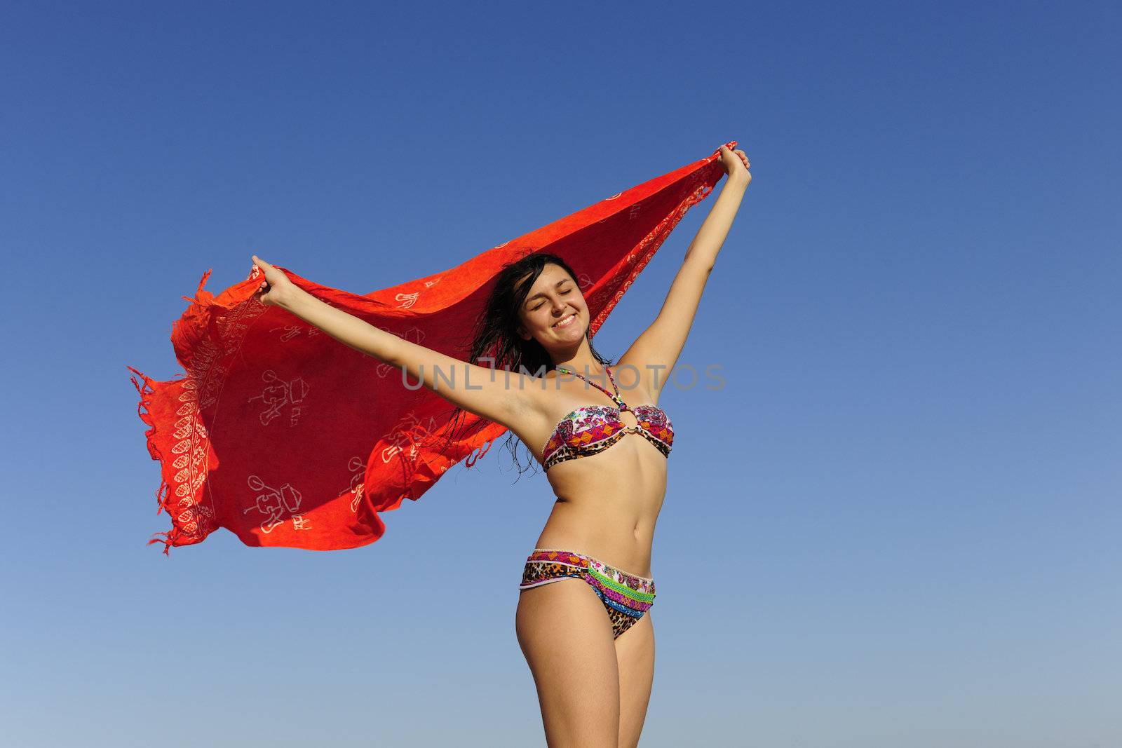 freedom: woman with beach towel against blue sky by mangostock
