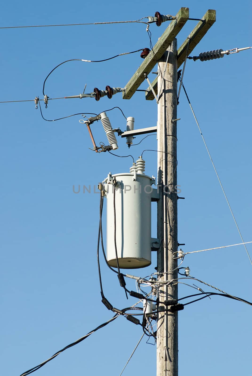 A transformer on a powerline pole shot against a blue sky