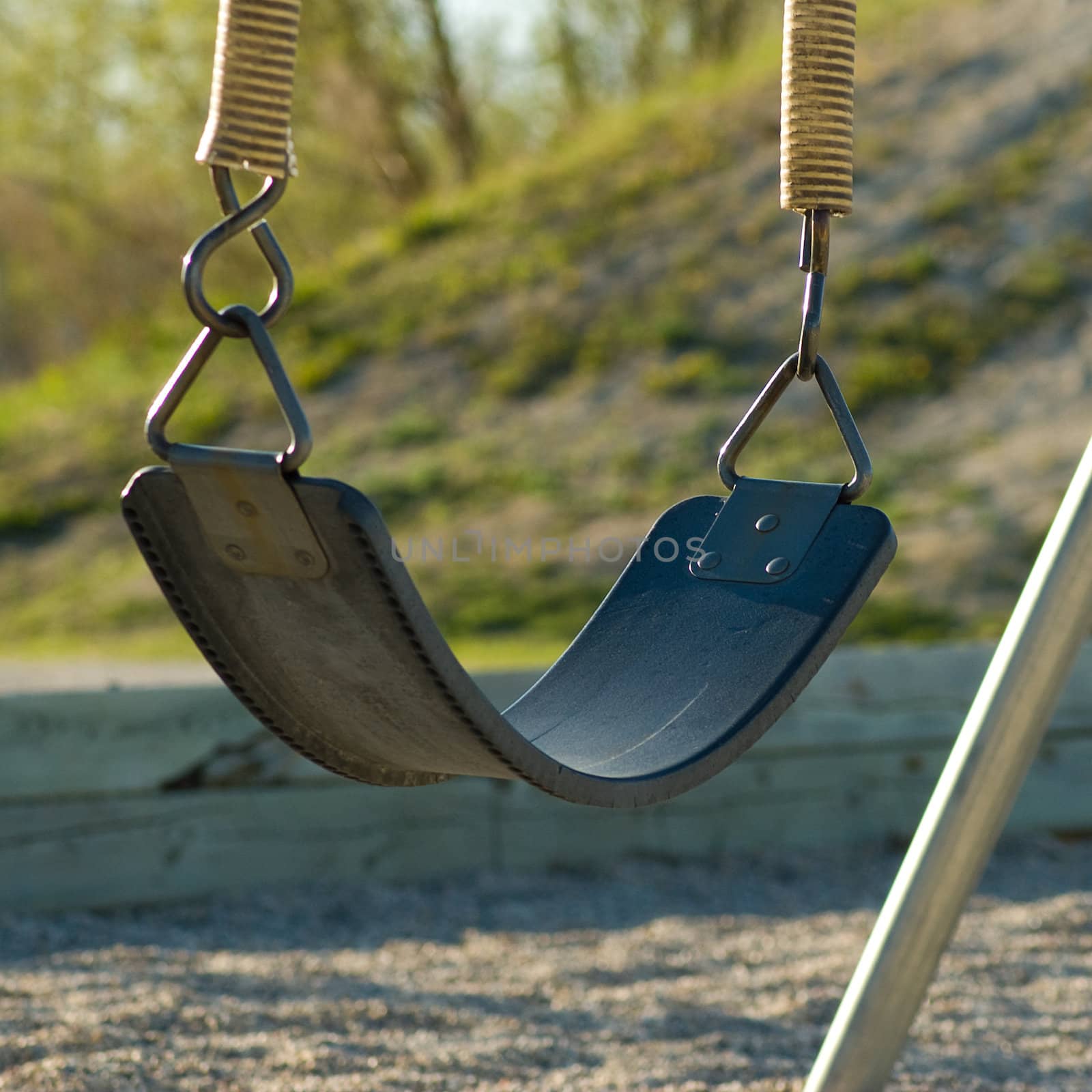 A single swing, sitting empty on a playground