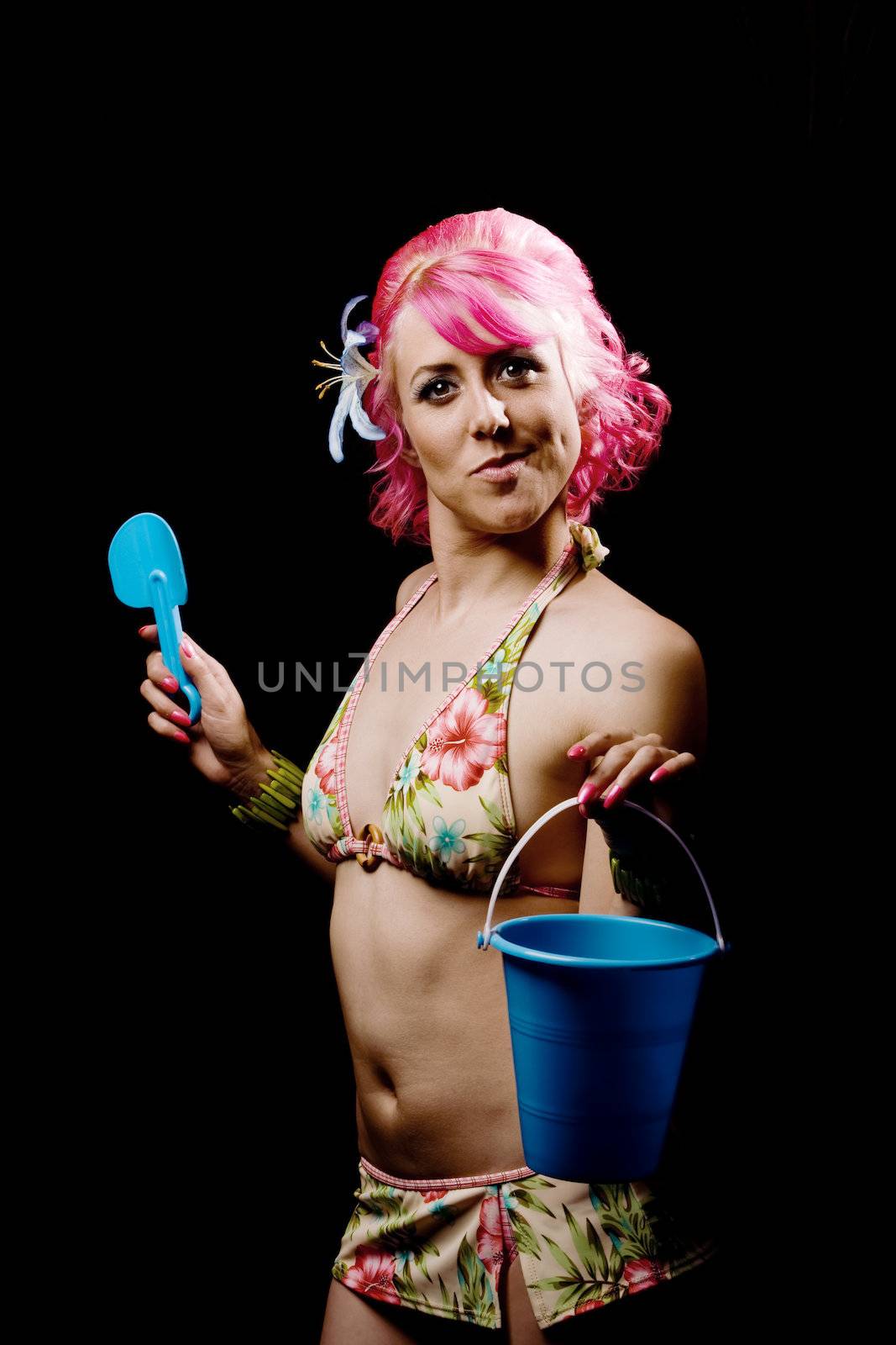 Pretty woman in a flowered bikini on a black background with beach toys