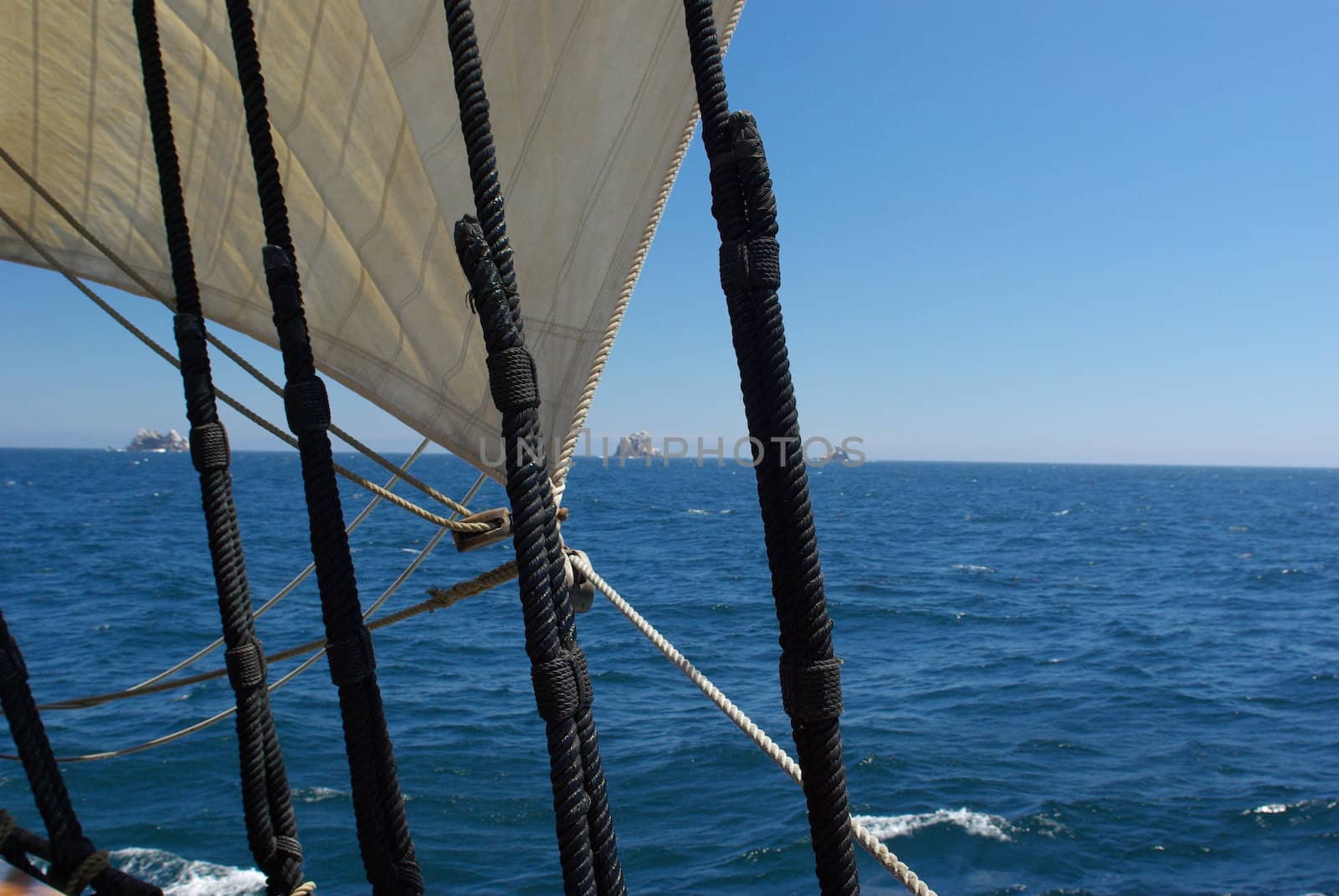 Three of the Farallon Islands viewed through the rigging of a sailing ship.