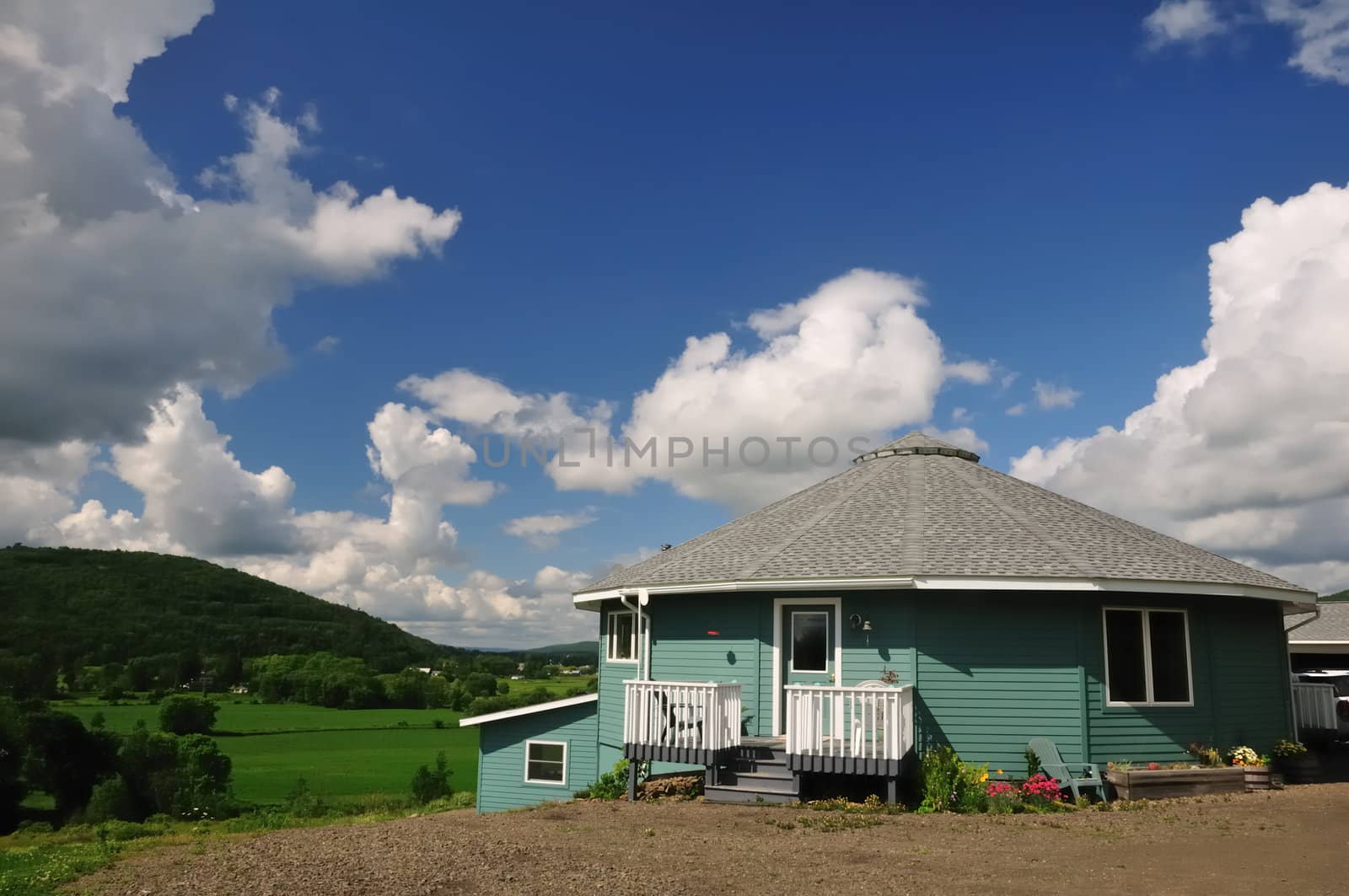 A sixteen-sided house perched on a hillside overlooking a lush green river valley.