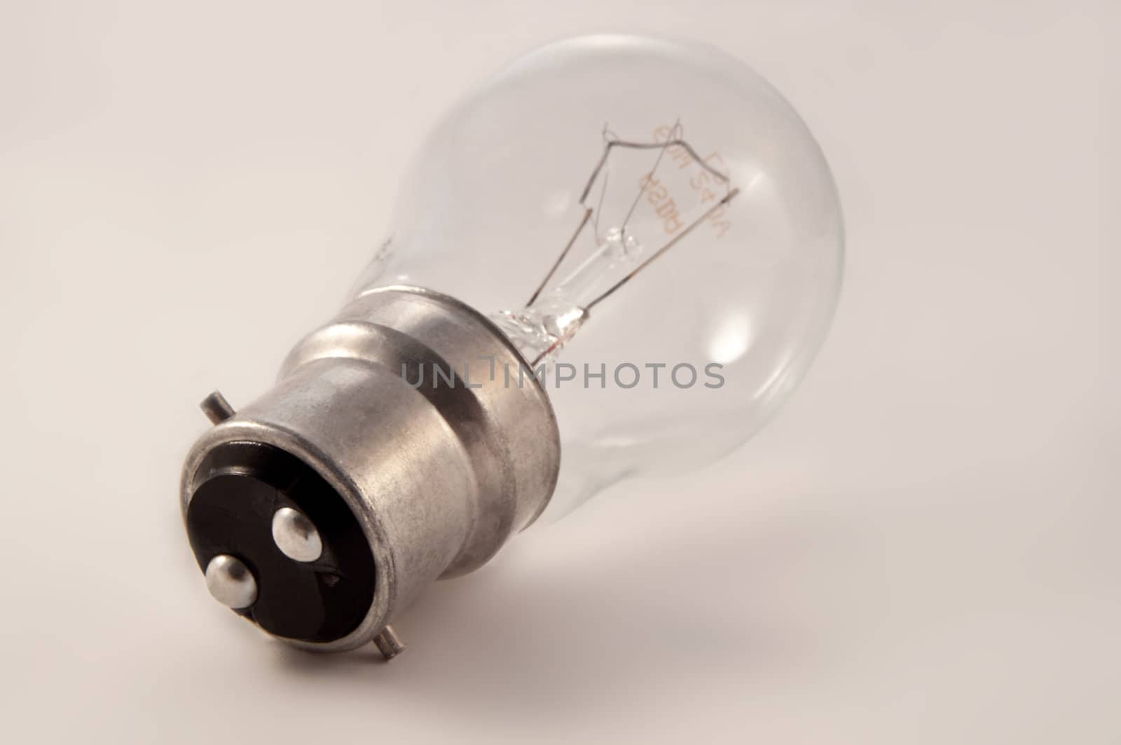 Close on an isolated clear glass light bulb arranged over light grey.