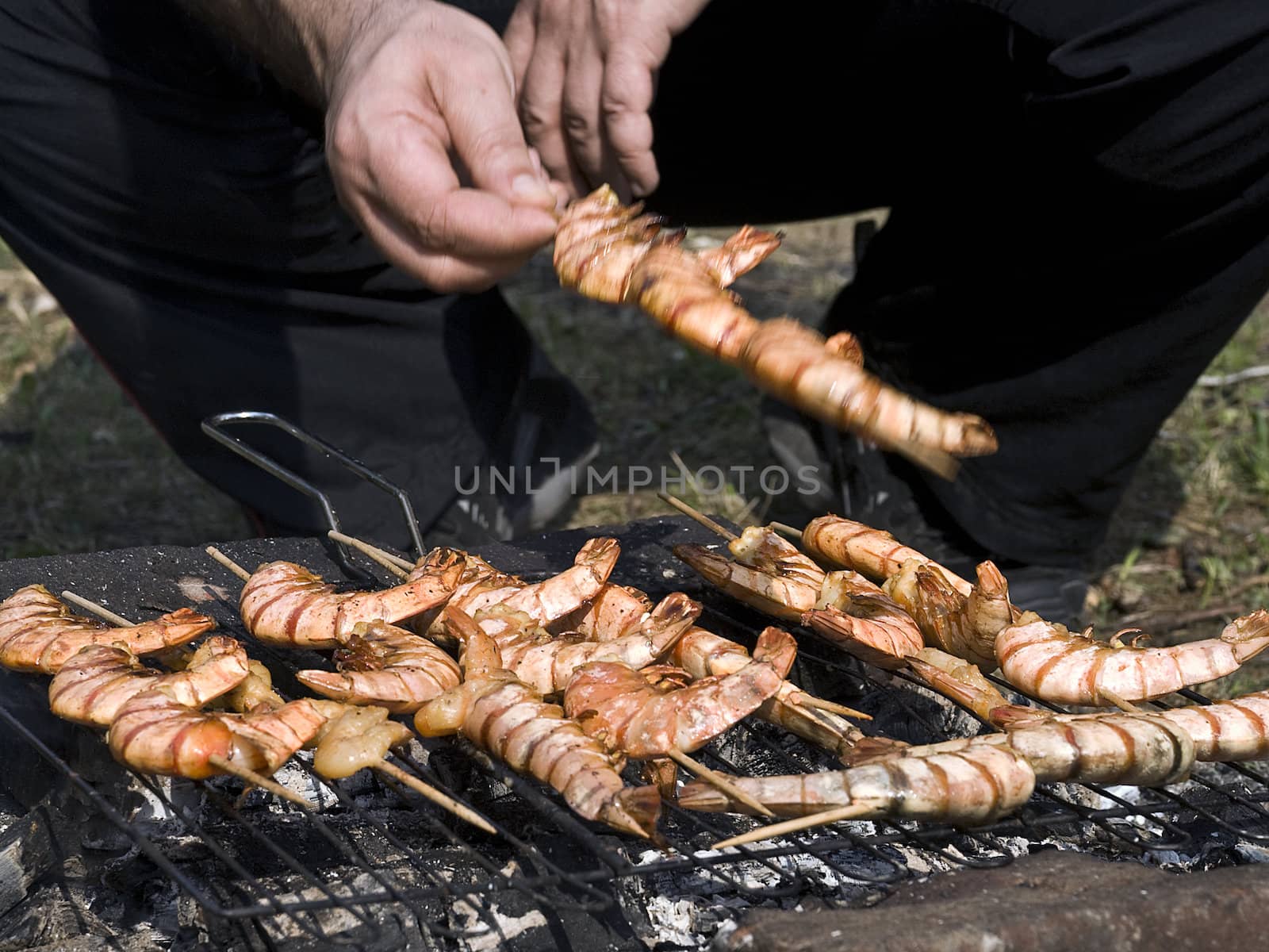 Man prepares shrimps on a grill by megann