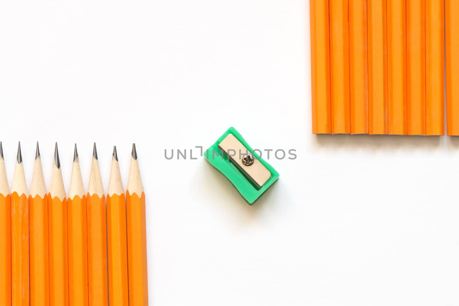 Few yellow wooden pencils lying in a row and sharpener on white background