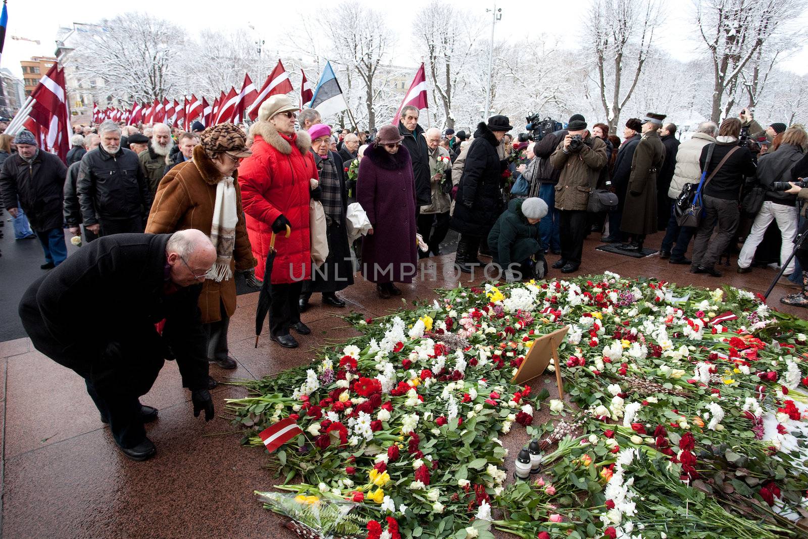 RIGA, LATVIA, MARCH 16, 2010: People lay dwn fowers at Freedom Monumunt. Commemoration of the Latvian Waffen SS unit or Legionnaires. The event is always drawing crowds of nationalist supporters and anti-fascist demonstrators. Many Latvians were forcibly called to join the Latvian SS Legion.