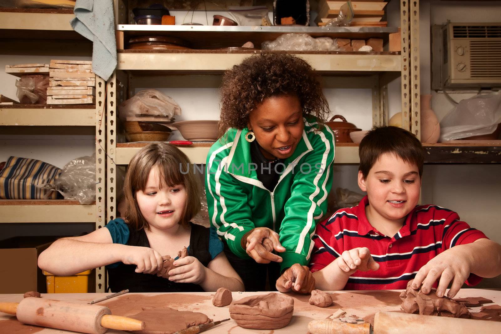 Teacher and young students having fun in clay studio