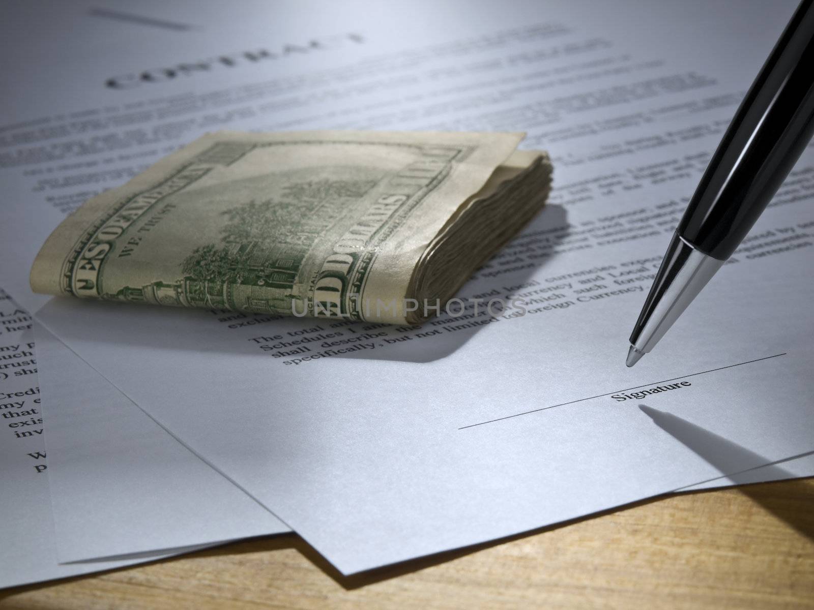 Close up of a pen about to sign the contract. Stack of money over it.