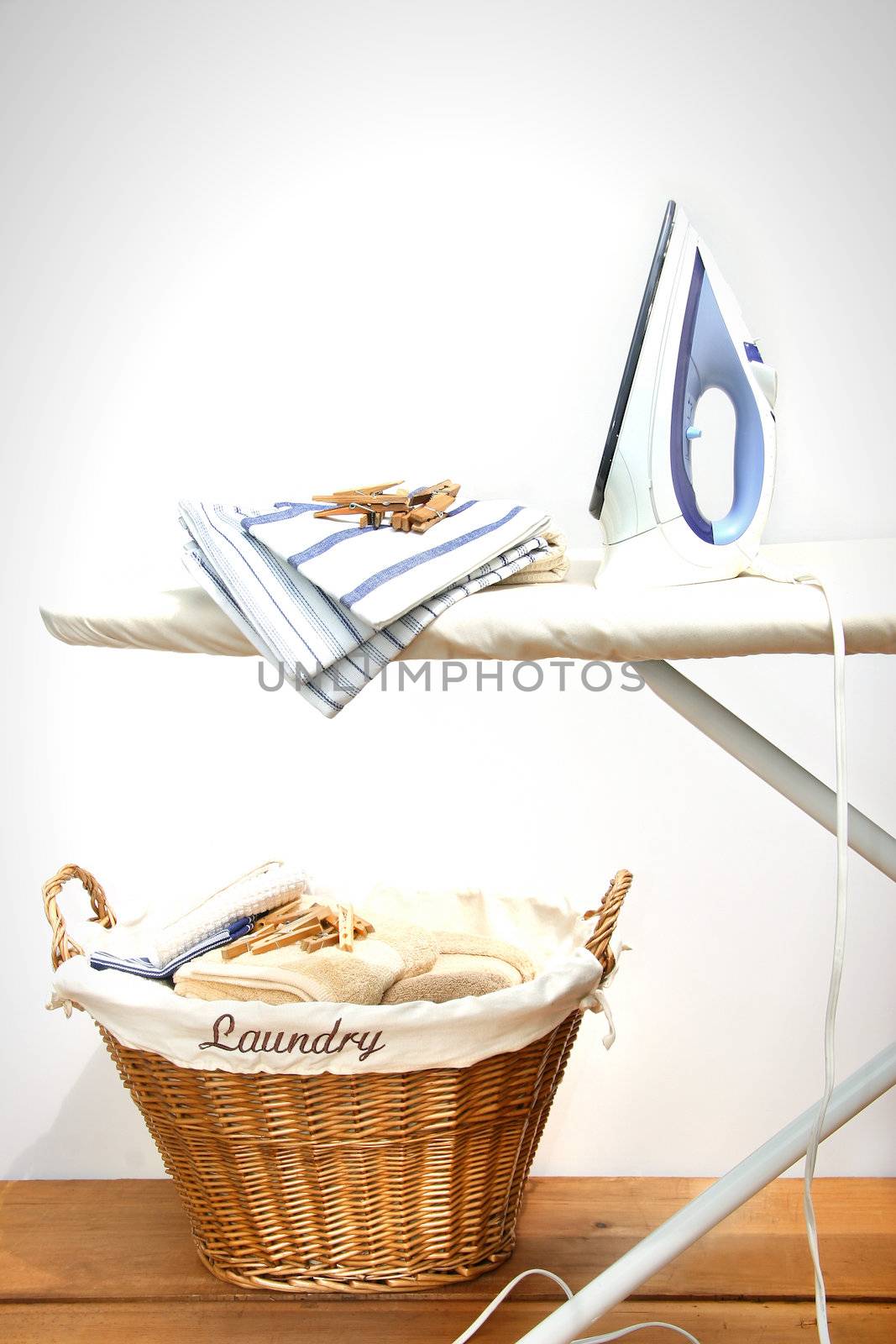 Ironing board with laundry against white background