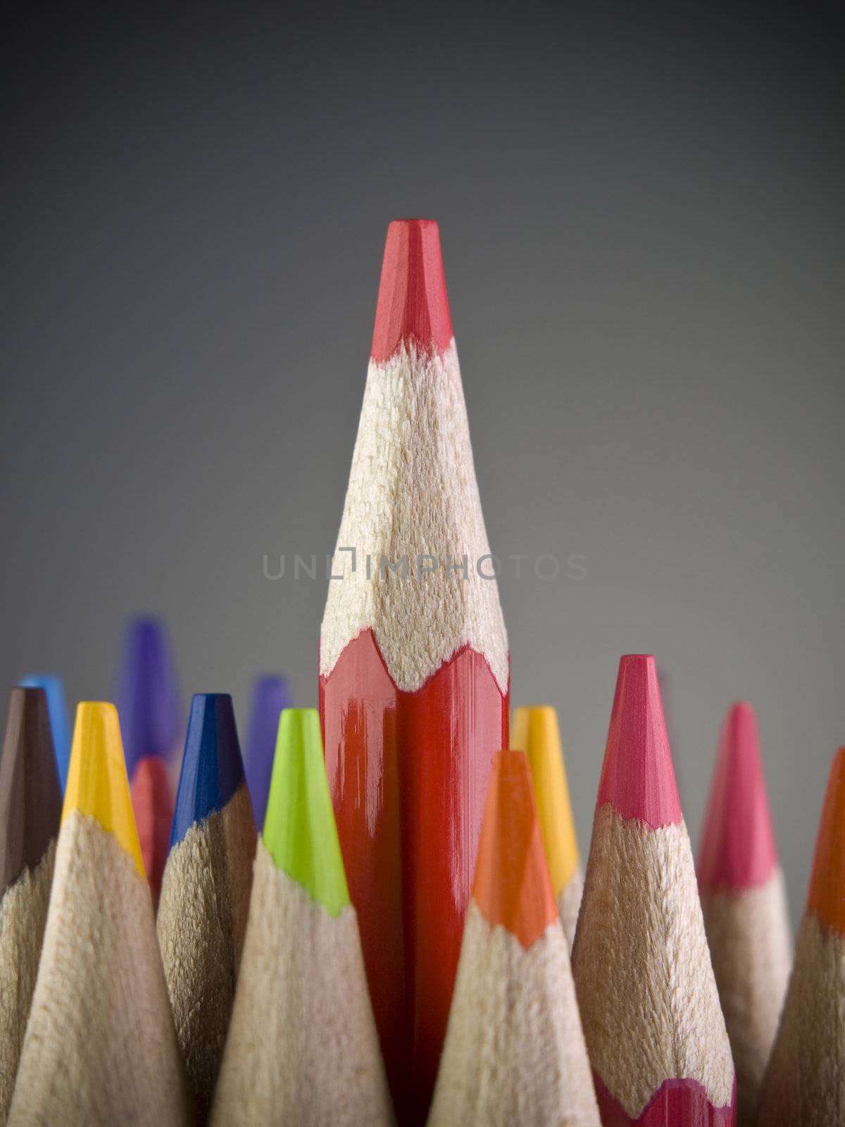 Red pencil coming out among many colored pencils.