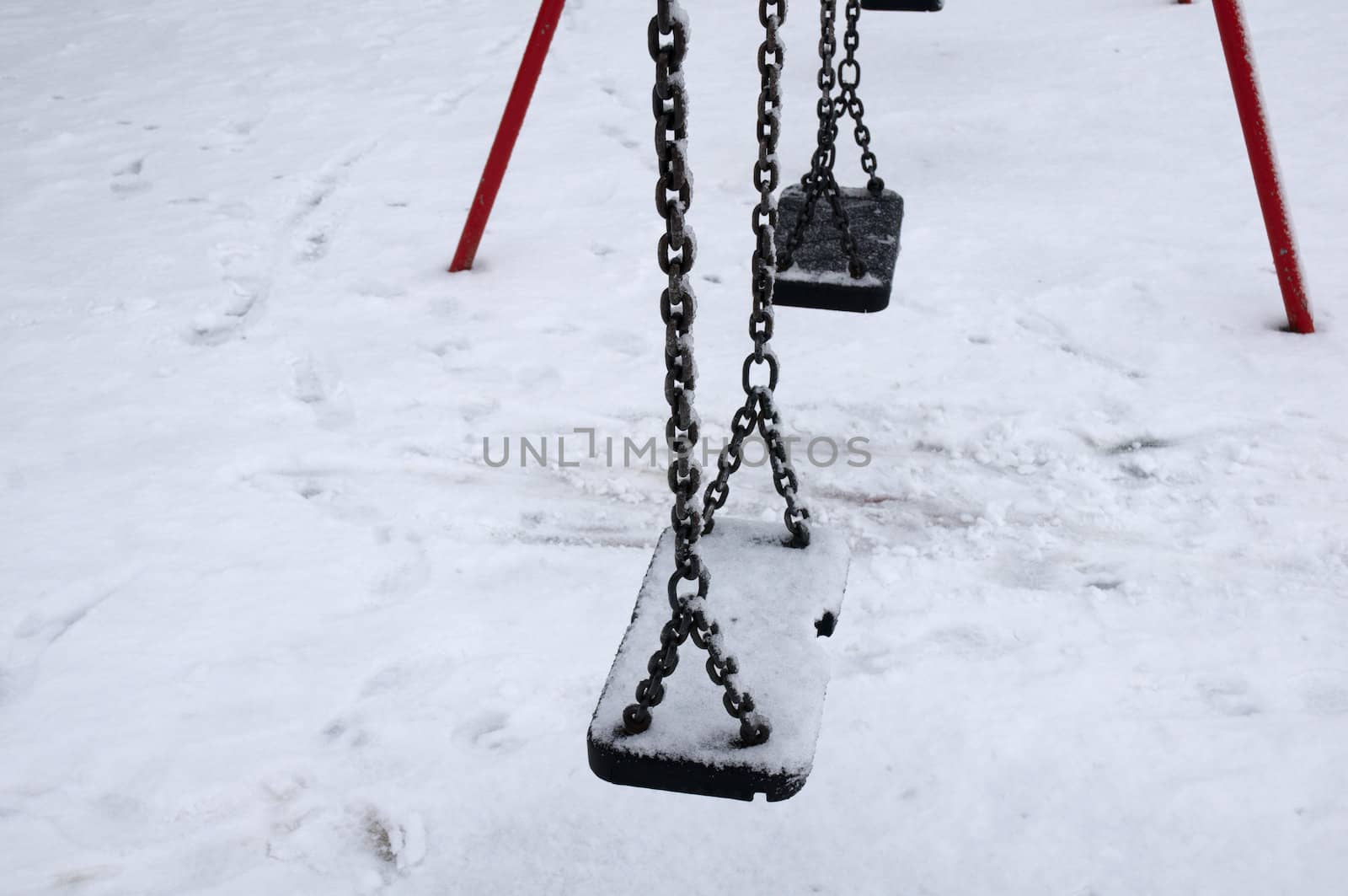 The seat of a swings covered in snow