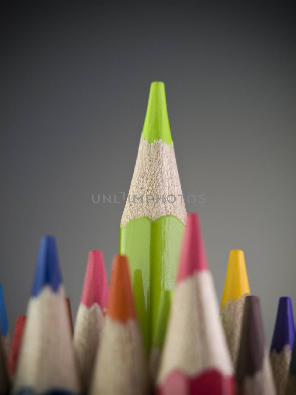 Green pencil coming out among many colored pencils.