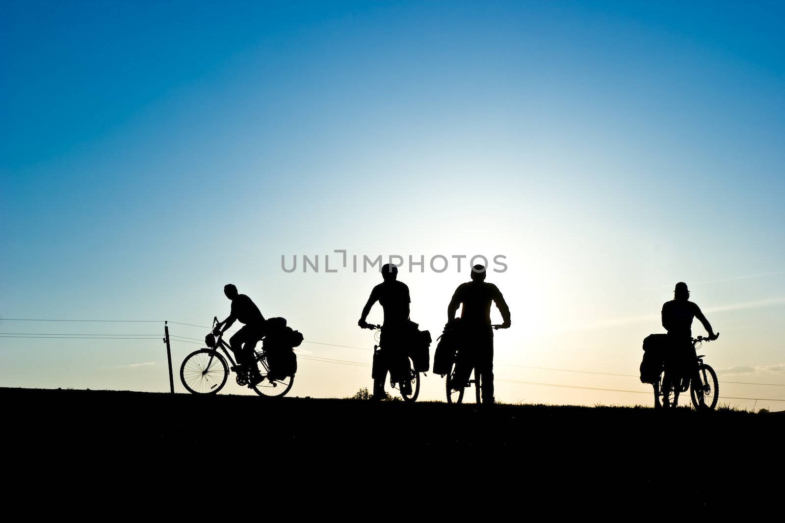 Group of Bicycle tourists on a road against sunset