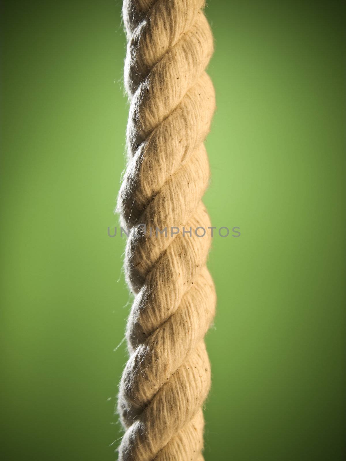 Close up of a brown rope over a green background.