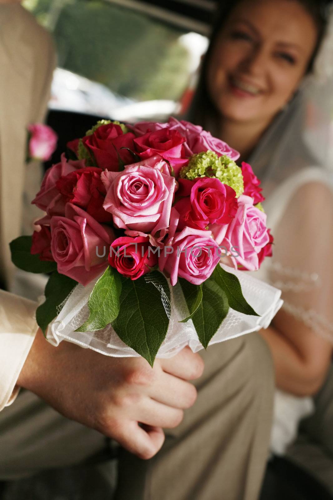 Bouquet of flowers on a background of a dress of the bride and a suit the groom. 