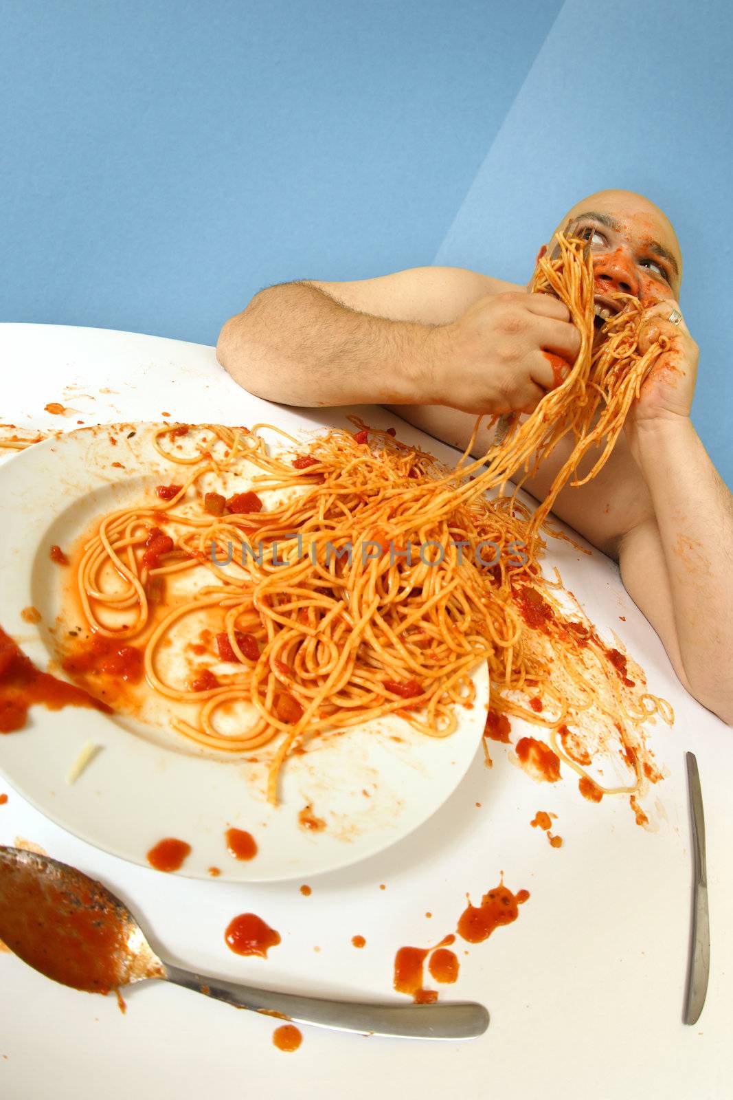 An overweight man enjoying a plate of spaghetti.  Shot with fish-eye lens.  Focus is on the face.
