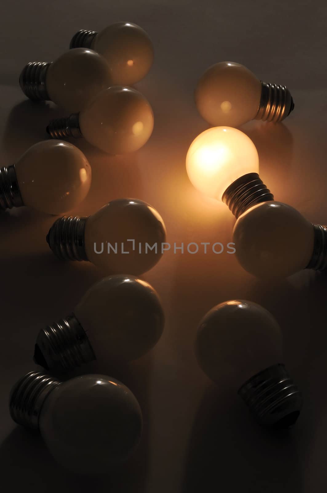 A figurative picture of light bulbs. One bright burning bulb with dull lamps. One bright mind/idea in a crowd.