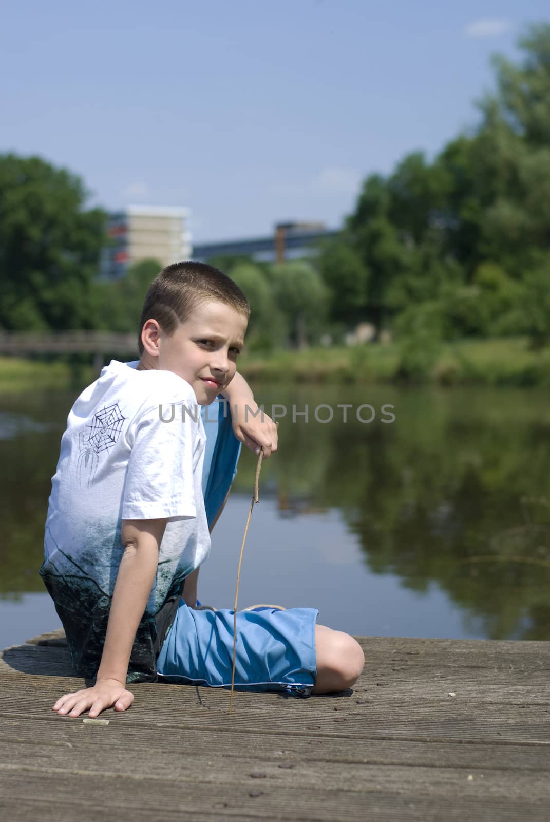 Boy sitting on a dock, looking a bit bored.