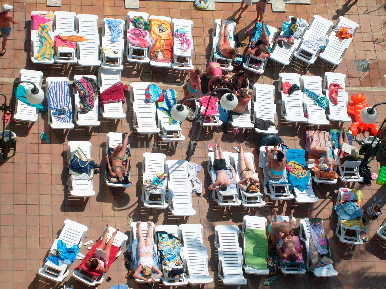 Overhead view of some sunbathers on sun terrace in tourist hotel.