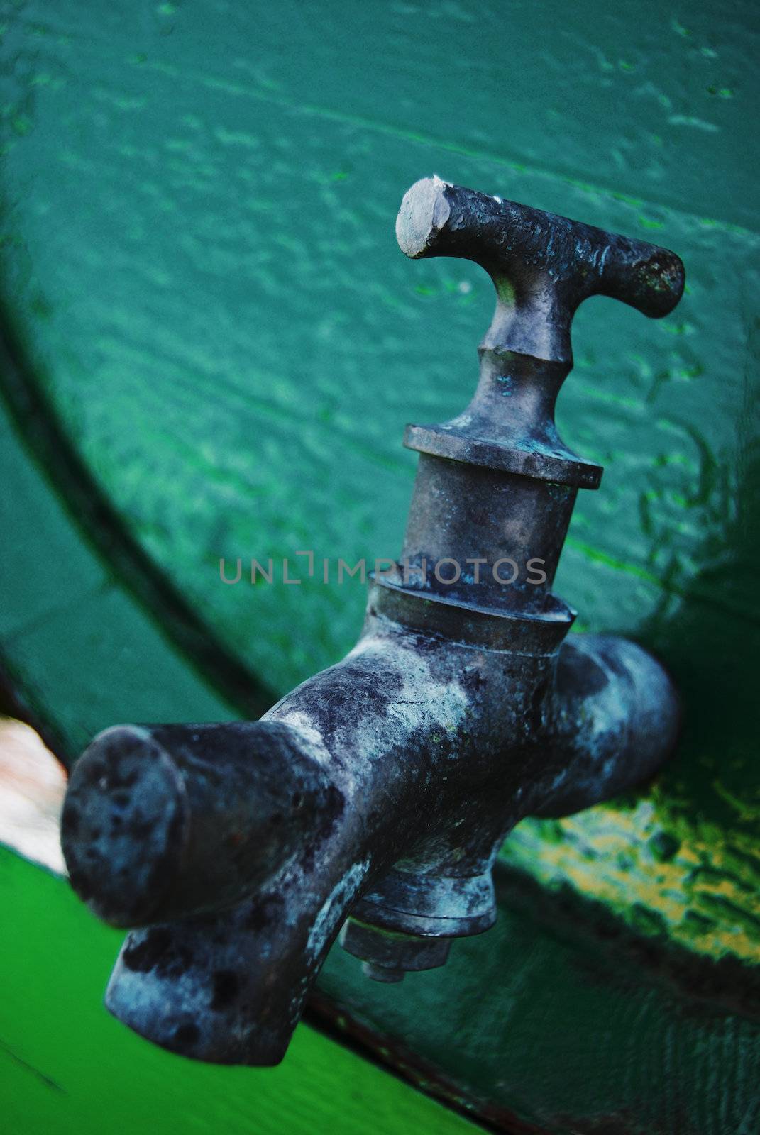 closeup of a water tap on a green barrel